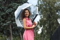 Young girl in a red dress with a transparent umbrella dancing in the rain standing in a puddle Royalty Free Stock Photo