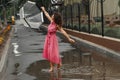 Young girl in a red dress with a transparent umbrella dancing in the rain standing in a puddle Royalty Free Stock Photo