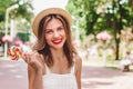 A young girl with red lipstick in a straw hat and a lollipop laughs and smiles in the park Royalty Free Stock Photo