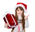 Young girl with red santa hat holding gift box and showing thumb up. isolated on white Royalty Free Stock Photo