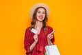 girl in a red summer dress, a straw hat smiles and holds shopping packages, a mobile phone and a credit card isolated on Royalty Free Stock Photo