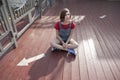 Young girl in a red wool sweater and jeans shorts is sitting on the pier Royalty Free Stock Photo