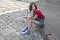 Young girl in a red wool sweater and jeans shorts is sitting on the steps Royalty Free Stock Photo