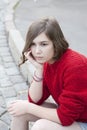 Young girl in a red wool sweater and jeans shorts is sitting on the steps Royalty Free Stock Photo