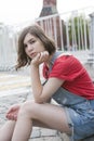 Young girl in a red wool sweater and jeans shorts is sitting on the steps Royalty Free Stock Photo