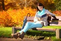 Young girl relaxing in autumnal park reading book Royalty Free Stock Photo