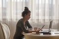 Young girl at a remote work at home sitting in the kitchen at a laptop