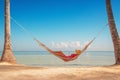 Young girl resting in a hammock under tall palm trees, tropical beach Royalty Free Stock Photo