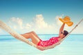 Young girl resting in a hammock under tall palm trees, tropical beach Royalty Free Stock Photo