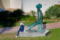 A young girl rests beside a statue outside Sir Thomas Brisbane Planetarium