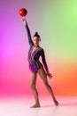 Young girl, rhythmic gymnast with red ball in motion, action isolated on multicolored neon background with copyspace for Royalty Free Stock Photo