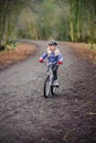 A young girl rides a bike along a country track towards the camera
