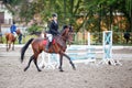 Young girl riding bay horse on show jumping