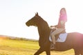 Young girl riding a dark horse in a field on a sunset Royalty Free Stock Photo