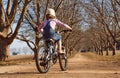 Young girl riding her bicycle bike down dirt road tree lined ave