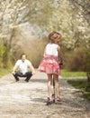 Young girl riding scooter away from camera to father in park Royalty Free Stock Photo