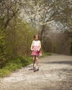 Young girl riding scooter on path through park Royalty Free Stock Photo