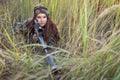 Young girl with a rifle peeking out of the grass Royalty Free Stock Photo