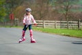 A young girl on roller blades and wearing protective equipment skates along a country road Royalty Free Stock Photo