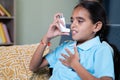 Young girl rubbing her chest after taking asthmatic inhaler at home - Concept of Teenager kids healthcare and medical Royalty Free Stock Photo