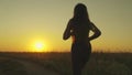 young girl runs across field sunset headphones. silhouette girl rays sunlight listens music. healthy image women health