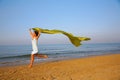 Young girl runs on edge of sea with yellow shawl