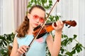 A young girl runs her bow across the strings of a violin and looks into the camera Royalty Free Stock Photo