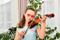 A young girl runs her bow across the strings of a violin and looks into the camera Royalty Free Stock Photo