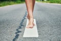 Young girl`s bare feet stand on the divivding road line Royalty Free Stock Photo