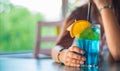 Young girl`s hand holding a glass with a blue lemonade cocktail with fruits Royalty Free Stock Photo