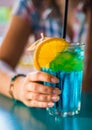 Young girl`s hand holding a glass with a blue lemonade cocktail with fruits Royalty Free Stock Photo