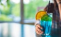 Young girl`s hand holding a glass with a blue lemonade cocktail with fruits Royalty Free Stock Photo