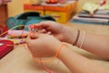 Young girl`s hands weaving a plastic bracelet close-up.