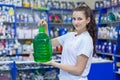 Young girl saleswoman offers a bottle of non-freezing cleaning liquid for washing the windshield of a car in an auto