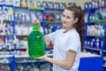 Young girl saleswoman offers a bottle of non-freezing cleaning liquid for washing the windshield of a car in an auto