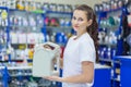 A young girl saleswoman offers a choice of engine oil for the engine in an auto parts store