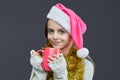 Young girl in a Santa hat holds a pink Cup. photo session in the Studio on a gray background Royalty Free Stock Photo