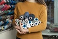 A young girl seamstress of Caucasian ethnicity in a workshop stands near a stand with threads of different colors. She holds