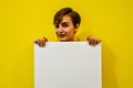 A young girl with short hair in an orange T-shirt smiles and holds a white poster with a place for the text. Royalty Free Stock Photo