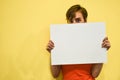A young girl with short hair in an orange T-shirt smiles and holds a white poster with a place for the text. Royalty Free Stock Photo
