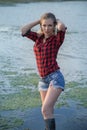 A young girl in short shorts and rubber boots went into the river Royalty Free Stock Photo