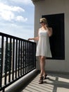 Young girl in short white dress at balcony in summer