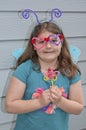 Girl with pipe cleaners craft projects of a butterfly and glasses Royalty Free Stock Photo