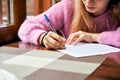 Young girl signs a document. student learns to write an abstract