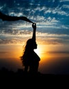 Young girl silhouette with shawl on background of beautiful cloudy blue sky with yellow golden sunset Royalty Free Stock Photo