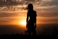 Young girl silhouette with shawl on background of beautiful cloudy sky with golden red sunset Royalty Free Stock Photo