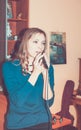 Young girl singing into a microphone at home. Retro toned image.