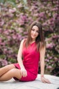 Young girl sist in front of sakura tree. Spring outside. Blossom tree Royalty Free Stock Photo