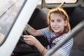 The young girl sits behind the wheel of an old car and smiles, she imagines that she travels in the country on a car Royalty Free Stock Photo