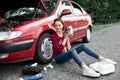 A young girl sits near a broken car and makes repairs to the electric generator, next to her there are bad parts, tools and first Royalty Free Stock Photo